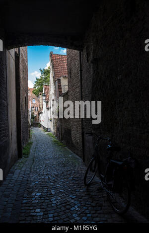 Prospettica di una strada stretta con vecchie case e una bicicletta parcheggiata in un vecchio centro storico della città medievale di Bruges, Belgio Foto Stock