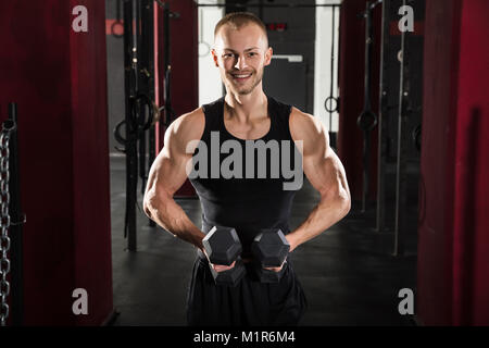 Ritratto di un giovane uomo che esercitano con il manubrio nella palestra Foto Stock