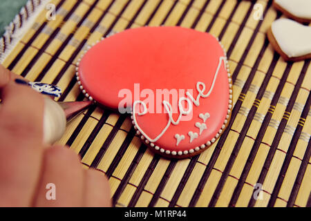 Gingerbread a forma di cuore decorata con smalto rosso con la scritta 'l'amore". Foto Stock