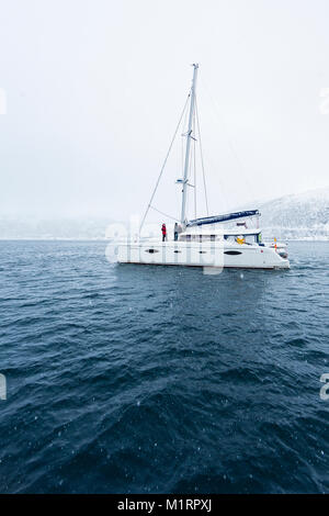 La Norvegia. Catamarano in acqua calma durante la nevicata. Foto Stock