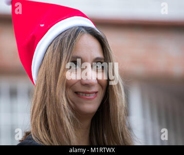 Close-up in posa con un berretto di Babbo Natale nel giardino della casa Foto Stock