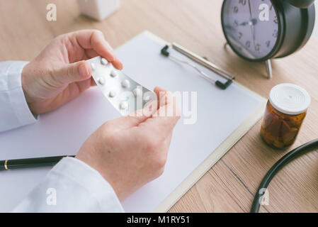 Medico donna holding non marcato compresse generici e medicinali, farmaci generici concetto, la prescrizione medicina e sanità Foto Stock