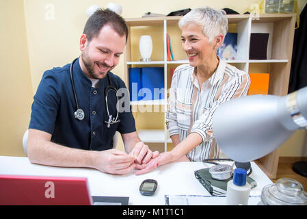 Donna anziana controllando il suo sangue in clinica Foto Stock