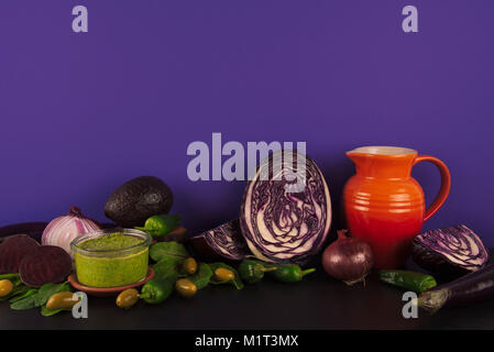 Assortimento di materie organiche e viola verdure verdi su sfondo viola. Foto Stock