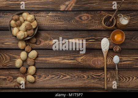 Sfondo di cibo. La cottura Ingredienti farina, uova, dadi, zucchero, frutta secca su un tavolo di legno. vista dall'alto. Copia dello spazio. Foto Stock