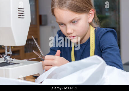 Una bimba di 8 anni, è filo di taglio del filato con le forbici Foto Stock