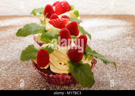 In casa deliziosi tortini di cioccolato con lamponi freschi e la crema sulla parte superiore. Deliziosa tortina per il giorno di San Valentino. Foto Stock