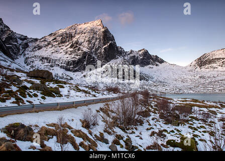 Montagne coperte di neve sulla strada per Nusfjord, Flakstadøya Isole Lofoten in Norvegia Foto Stock