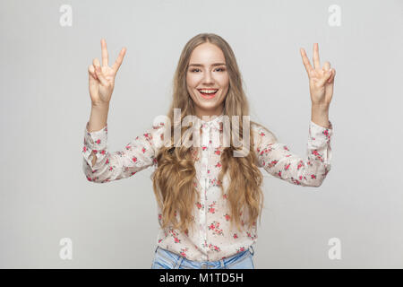 Giovane donna adulta che mostra segni di pace e toothy sorridente. Studio shot Foto Stock