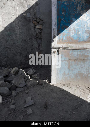 Vecchio Blu porta di legno in una casa in rovina, a zig-zag ombra cade sullo sfondo, un design sfondo grunge, un telaio verticale. Foto Stock