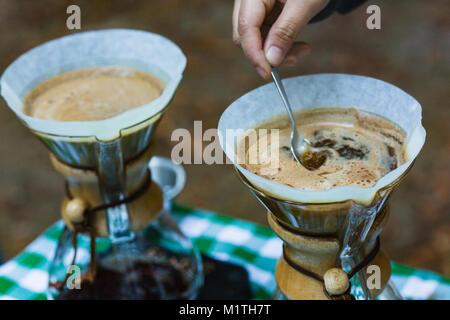 Barista suscita versare il caffè in vetro artigiano birraio mentre all'aperto Foto Stock