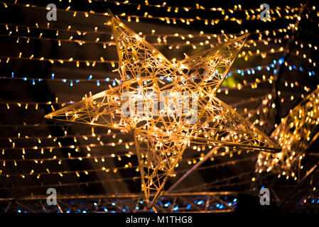 Stella brillante e luce su strisce scure, notte romantica sullo sfondo del cielo. Mercatino di Natale e decorazioni in centro citta'. Bellissimo sfondo di Natale Foto Stock