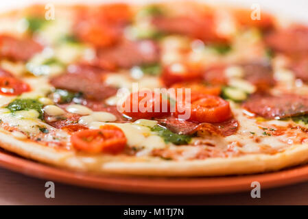 Una deliziosa pizza con pomodori, salame vicino Foto Stock