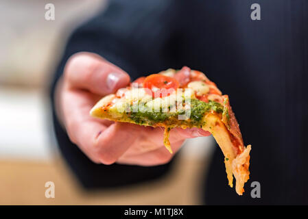 Mano trattiene fetta tagliata vicino pizza Foto Stock