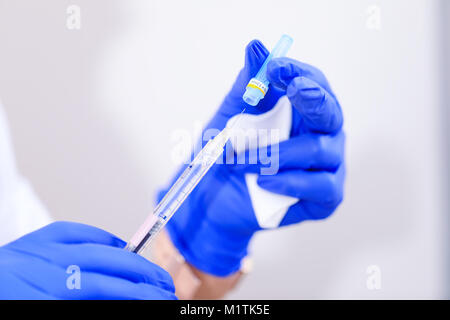 La mano di un medico tenendo la siringa medica. Siringa medica sulla mano del medico durante un intervento chirurgico. Ospedale e concetto medico. Foto Stock
