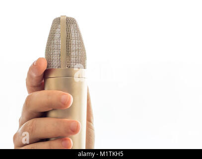 Un microfono è su un mic stand. Una mano mano d'uomo è di tenere in mano il microfono. Lo sfondo è tutto bianco. Foto Stock