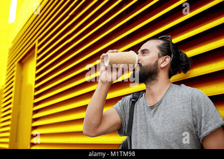 Uomo di bere il caffè dal bicchiere di carta sulla parete Foto Stock