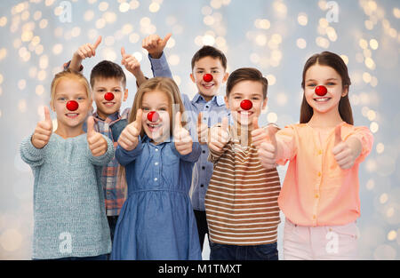 Dei bambini felici che mostra i pollici fino al naso rosso giorno Foto Stock