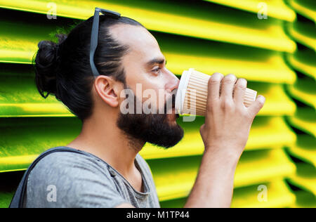 Uomo di bere il caffè dal bicchiere di carta sulla parete Foto Stock