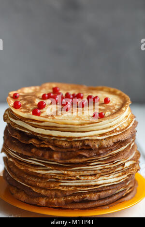 Alta pila di classico russo frittelle sottili con ribes rosso bacche . Stile rustico. Tradizionale per il pancake russo settimana (Maslenitsa) Foto Stock