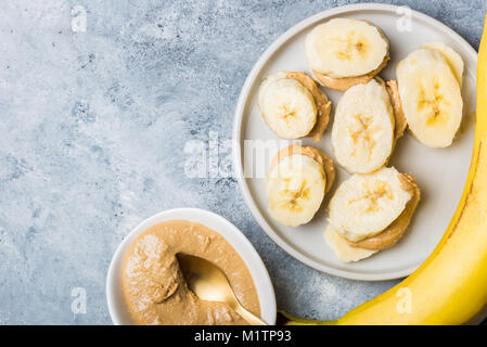 Light Snack sani realizzato da fettine di banana e anacardi burro su sfondo grigio Foto Stock