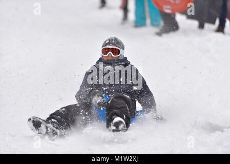 Little Boy correre sulla neve slitte in inverno Foto Stock