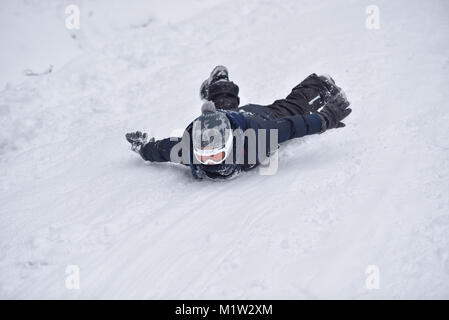 Little Boy scorre sulla neve in inverno Foto Stock