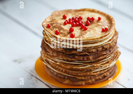 Alta pila di classico russo frittelle sottili con ribes rosso. Stile rustico. Tradizionale per il pancake russo settimana Maslenitsa. Foto Stock
