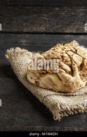 Radice di sedano e tela su legno scuro dello sfondo. Foto Stock