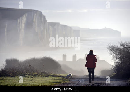 Signora cani a piedi nella nebbia vicino la mitica sette sorelle chalk cliffs, East Sussex, Regno Unito Foto Stock