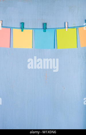 Cinque fogli di carta appeso a una fune su un blu sullo sfondo di legno. Foto Stock