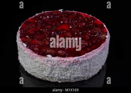 Grande torta in scaglie di noce di cocco con una ciliegia in jelly su sfondo nero Foto Stock