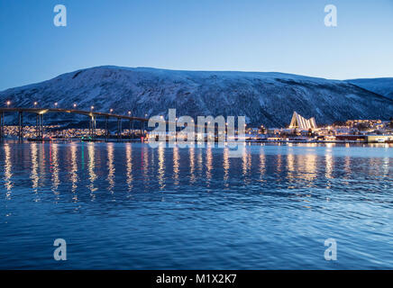 Vista dello Skyline di Tromsø, Norvegia, inclusa la Cattedrale Artica e Tromsøbrua (Tromsø Bridge), riflesso nell'acqua durante la notte polare in inverno. Foto Stock