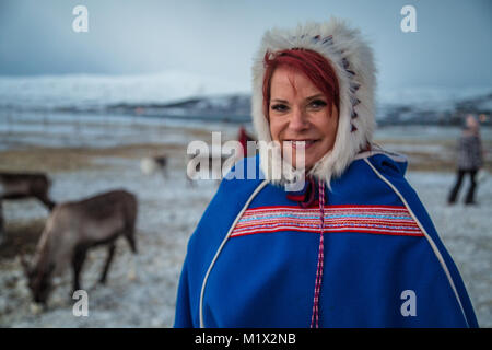 Un ritratto di un redhead Sami donna nel tradizionale abito Sami su una fattoria di renne al di fuori di Tromsø, Norvegia, in inverno polare. Foto Stock