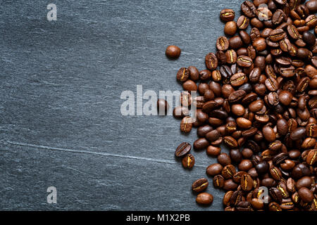 Chicchi di caffè tostati contro sfondo rustico con un buon spazio di copia Foto Stock