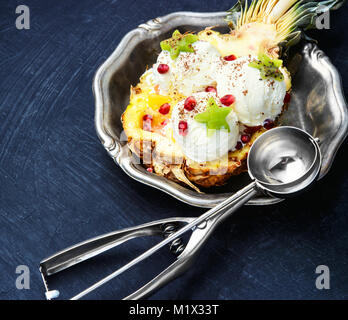 Il gelato in vaschetta di ananas sul blu scuro tabella Foto Stock