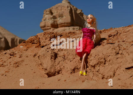 Barbie ragazze vestito di rosso e blu sono in posa per la modellazione di foto nel deserto rocce sulla posizione Foto Stock