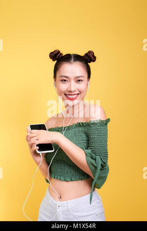 Studio colorato ritratto di felice giovane donna asiatica con gli auricolari è ballare e cantare. Foto Stock