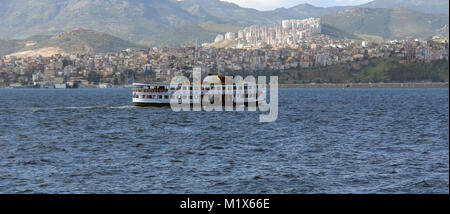 Un piccolo traghetto sulle onde del mare Egeo e di un pittoresco panorama della Baia di Izmir, Turchia. Foto Stock