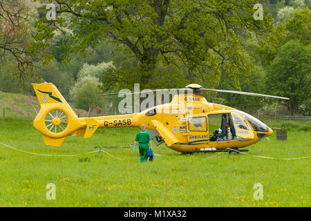 Un aereo ambulanza terre e decolla da un campo nei pressi di alberi e linee di alimentazione, Assistere una persona infortunata. Foto Stock