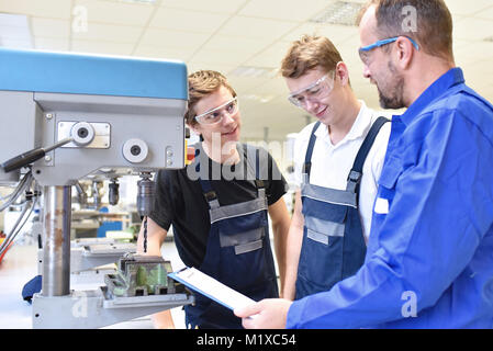 Trainer e apprendista in tecniche di formazione professionale in una macchina di foratura Foto Stock