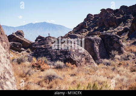 Donna sorge sulla sommità di una grande pietra nella Happy Boulder arrampicata su roccia area vicino Vescovo, California Foto Stock