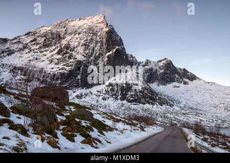 Montagne coperte di neve sulla strada per Nusfjord, Flakstadøya Isole Lofoten in Norvegia Foto Stock