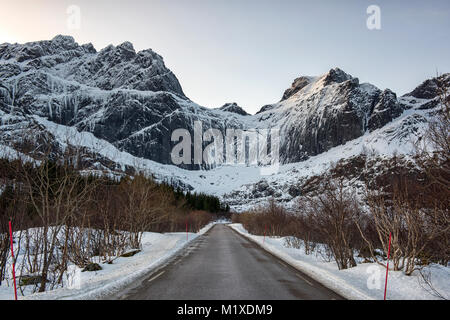 Montagne coperte di neve sulla strada per Nusfjord, Flakstadøya Isole Lofoten in Norvegia Foto Stock