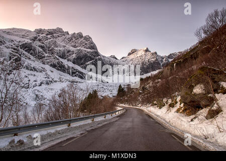 Montagne coperte di neve sulla strada per Nusfjord, Flakstadøya Isole Lofoten in Norvegia Foto Stock