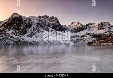 Montagne coperte di neve sulla strada per Nusfjord, Flakstadøya Isole Lofoten in Norvegia Foto Stock