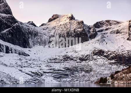 Montagne coperte di neve sulla strada per Nusfjord, Flakstadøya Isole Lofoten in Norvegia Foto Stock