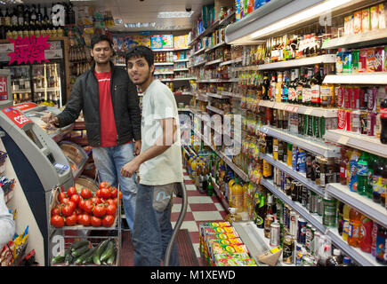 Un 'corner shop" e i suoi dipendenti asiatici su un Sabato notte, Stratford, East London, Regno Unito Foto Stock