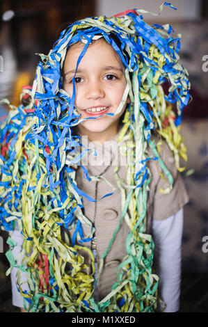 Bambino bambina con streamers intorno al suo collo e la testa per la festa di carnevale in casa sua Foto Stock