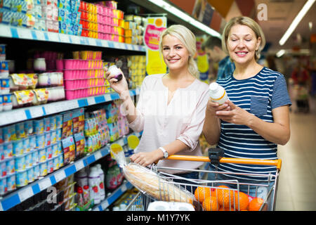 Clienti di sesso femminile la scelta di yogurt alla frutta e budino al negozio Foto Stock